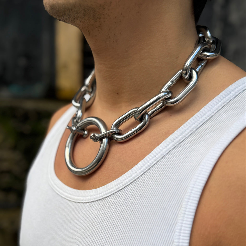 Person wearing a large silver chain necklace against a blurred background