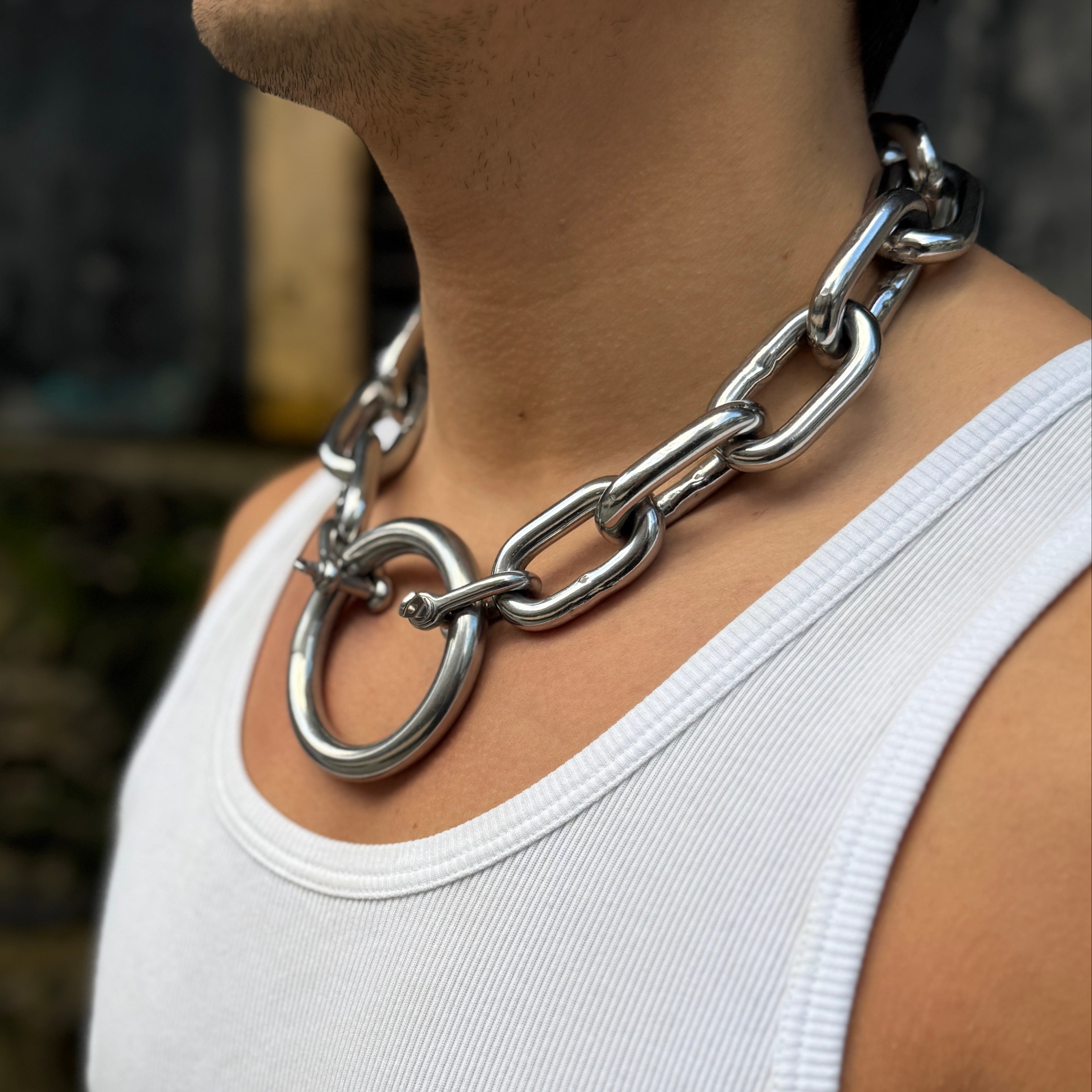 Person wearing a large silver chain necklace against a blurred background